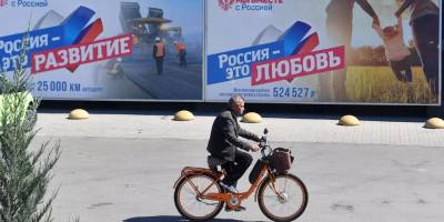 Чоловік їде на велосипеді повз магазин в окупованому Мелітополі на якому розміщенні російські пропагандистські рекламні борди від спонсорованої РФ організації "Ми разом з Росією", яка діє на ТОТ України. РИА Новости